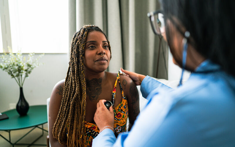 A young Black woman gets examined by her doctor.