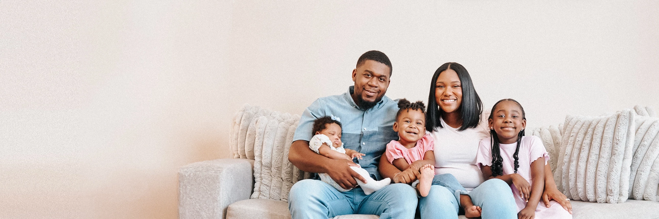 LMCU members sitting together on a couch, with one person holding a sleeping infant.
