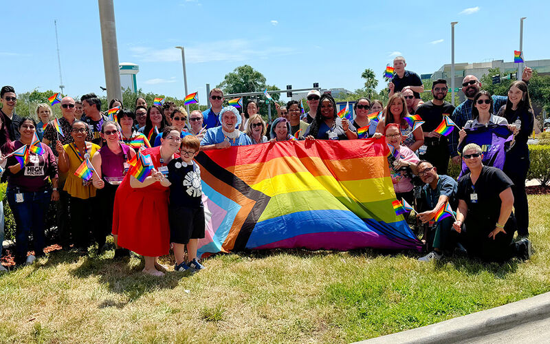 Moffitt team members stand with the Progressive Pride Flag in 2024