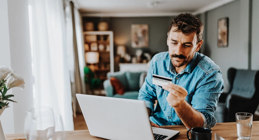 Young man using his credit card on the laptop