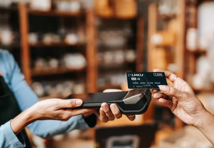 Customer taps a Max Rewards credit card on payment terminal at checkout. 