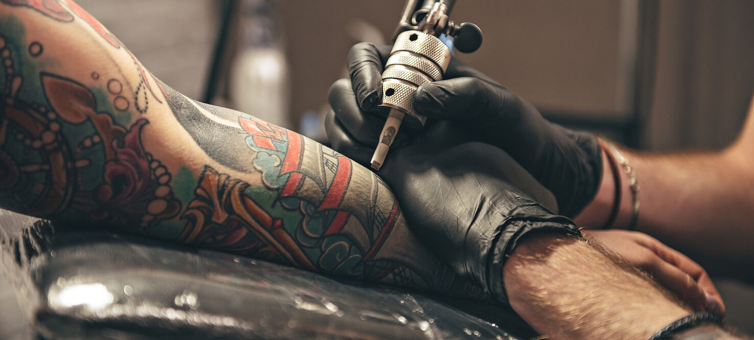 close up of a tattoo artist working on a tattoo on someone's arm