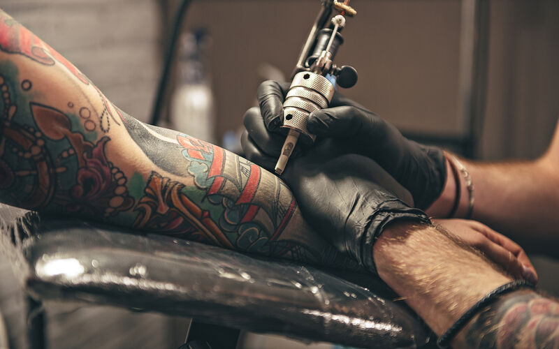 close up of a tattoo artist working on a tattoo on someone's arm