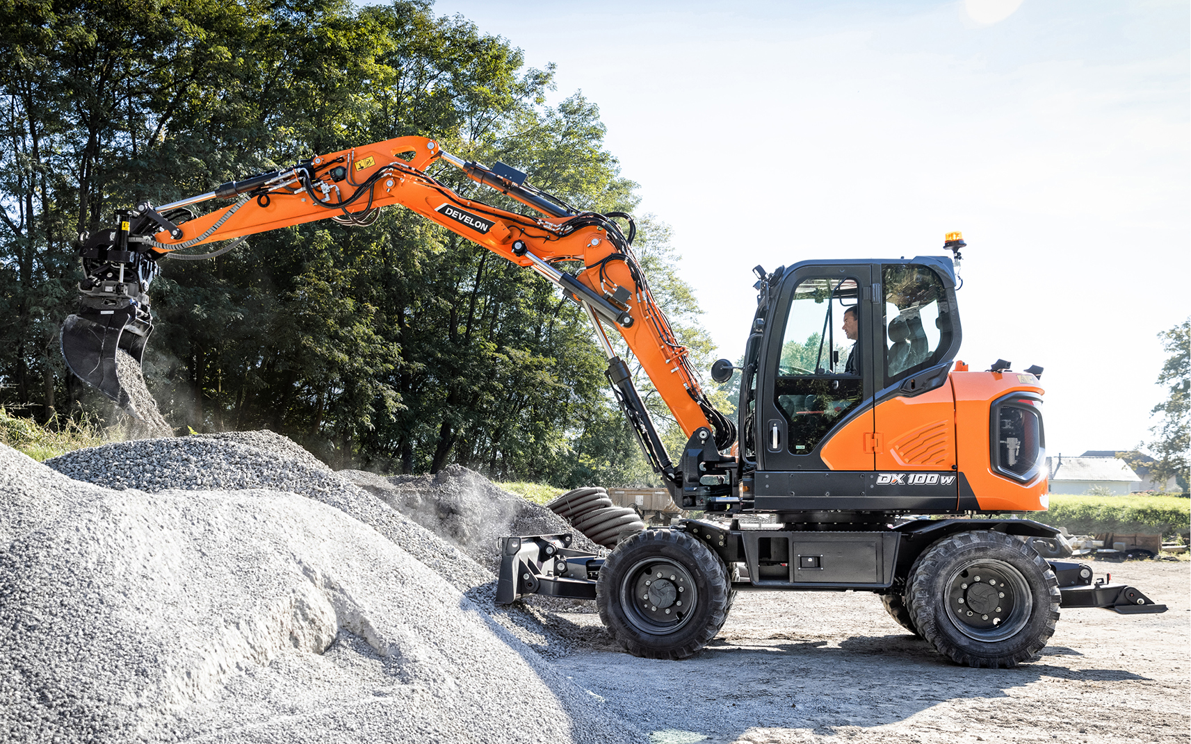 A DX100W-7 mini wheel excavator empties gravel from a bucket.