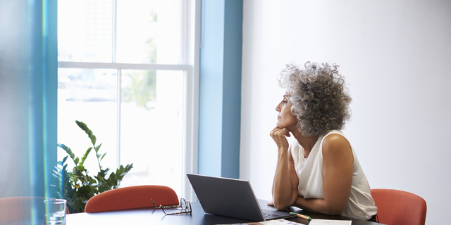 Middle aged woman looking out of the window in the boardroom