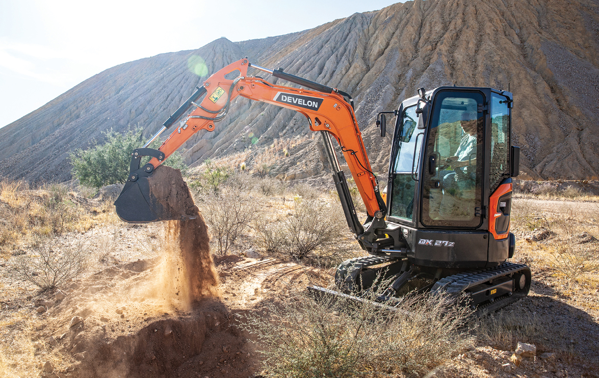 DEVELON mini excavator digs into rocky, hard ground on a job site.