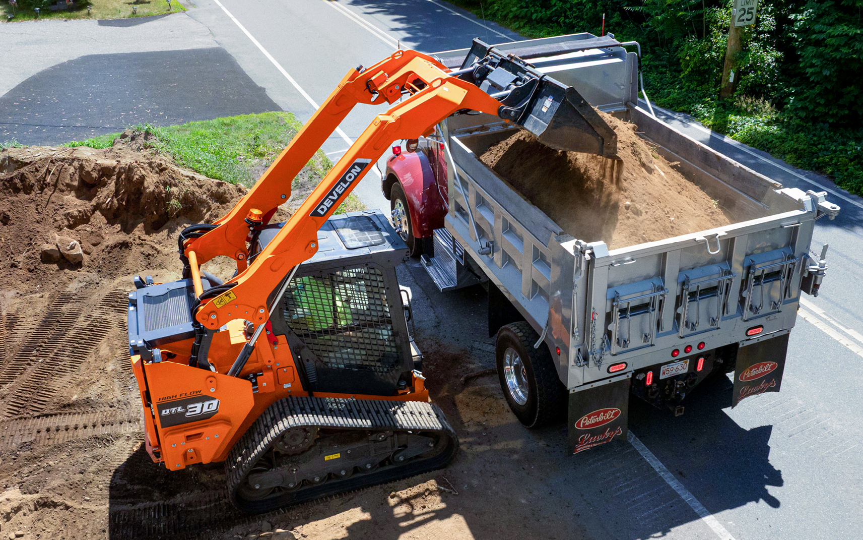 DEVELON DTL30 compact track loader dumping dirt into a high-sided dump truck.