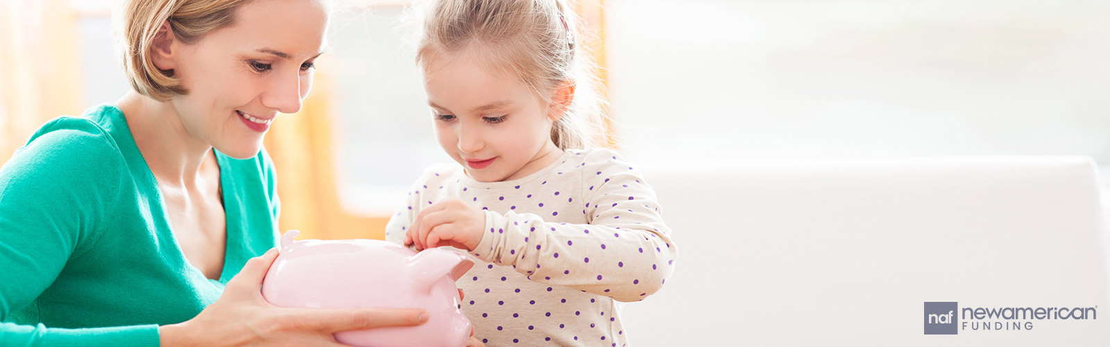 a mother holding a piggy bank while her daughter puts a coin in it