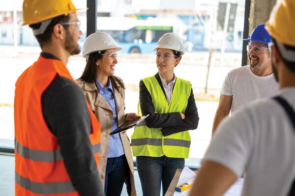 BICSI project managers and field technicians reviewing installation plans with safety gear