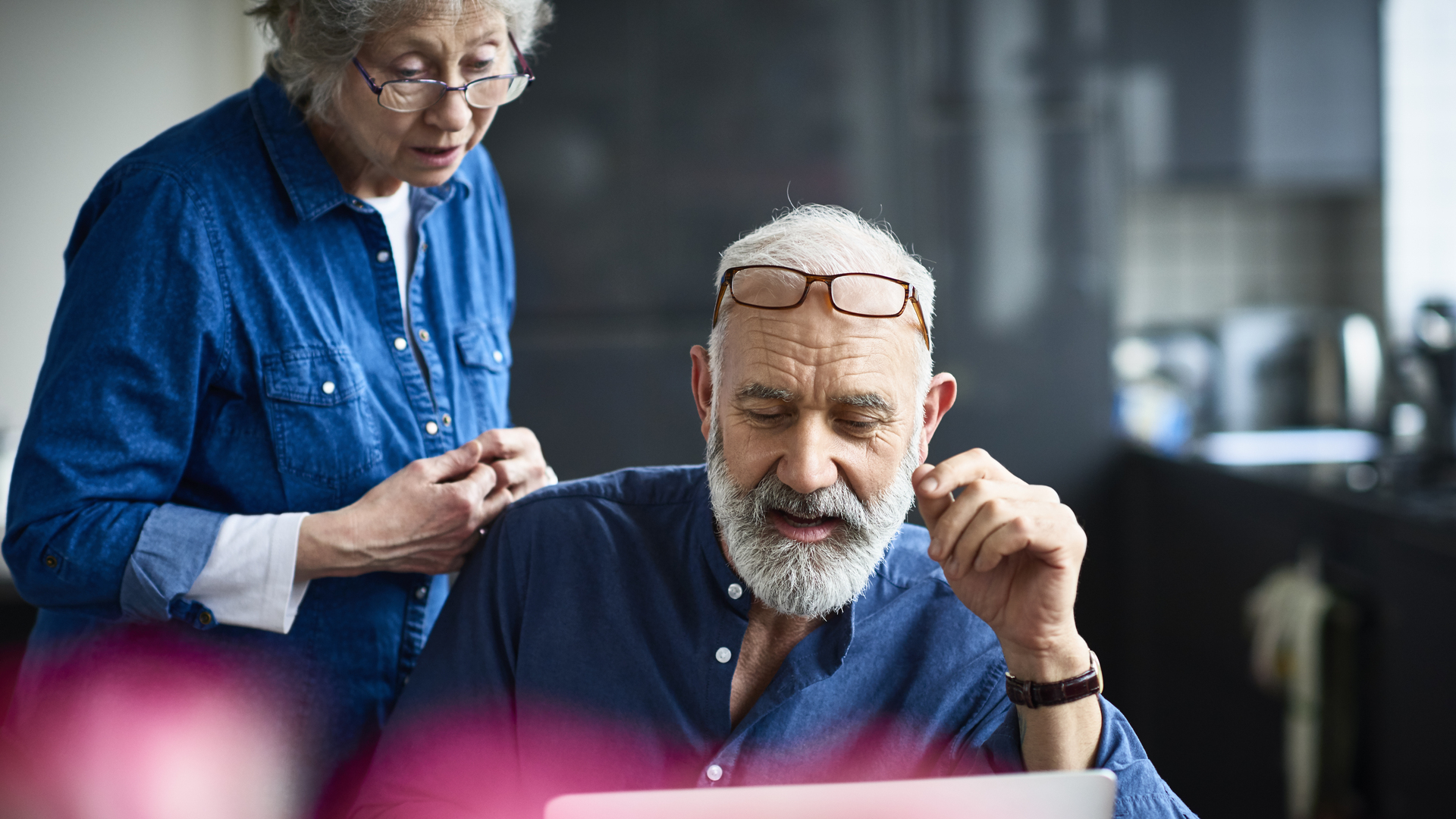 Hipster senior man with beard using laptop and woman watching