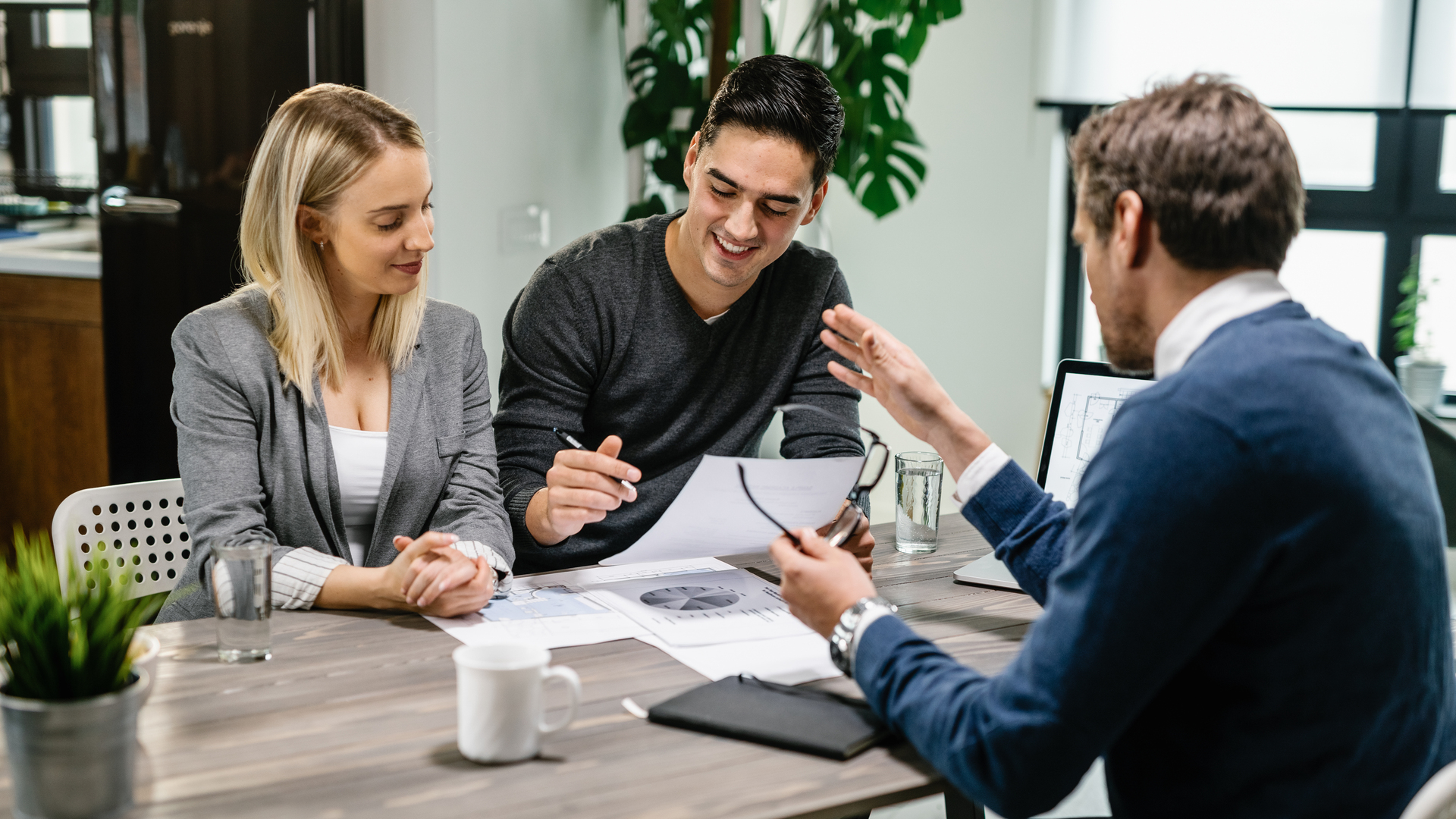 Happy couple going through paperwork while having meeting with financial advisor.