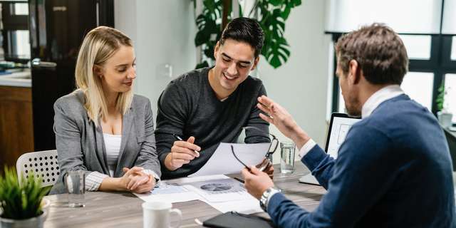 Happy couple going through paperwork while having meeting with financial advisor.