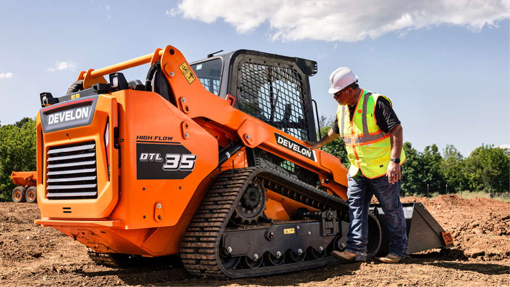 An operator inspects their DEVELON DTL35 compact track loader.