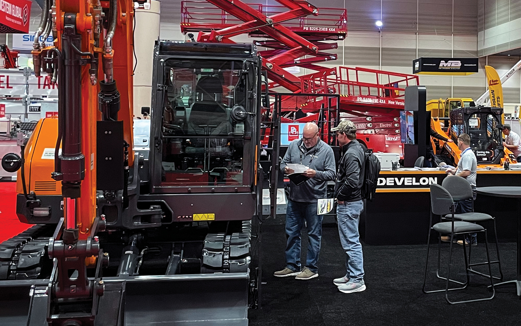 A DEVELON employee in The ARA Show exhibit answers questions about a mini excavator.