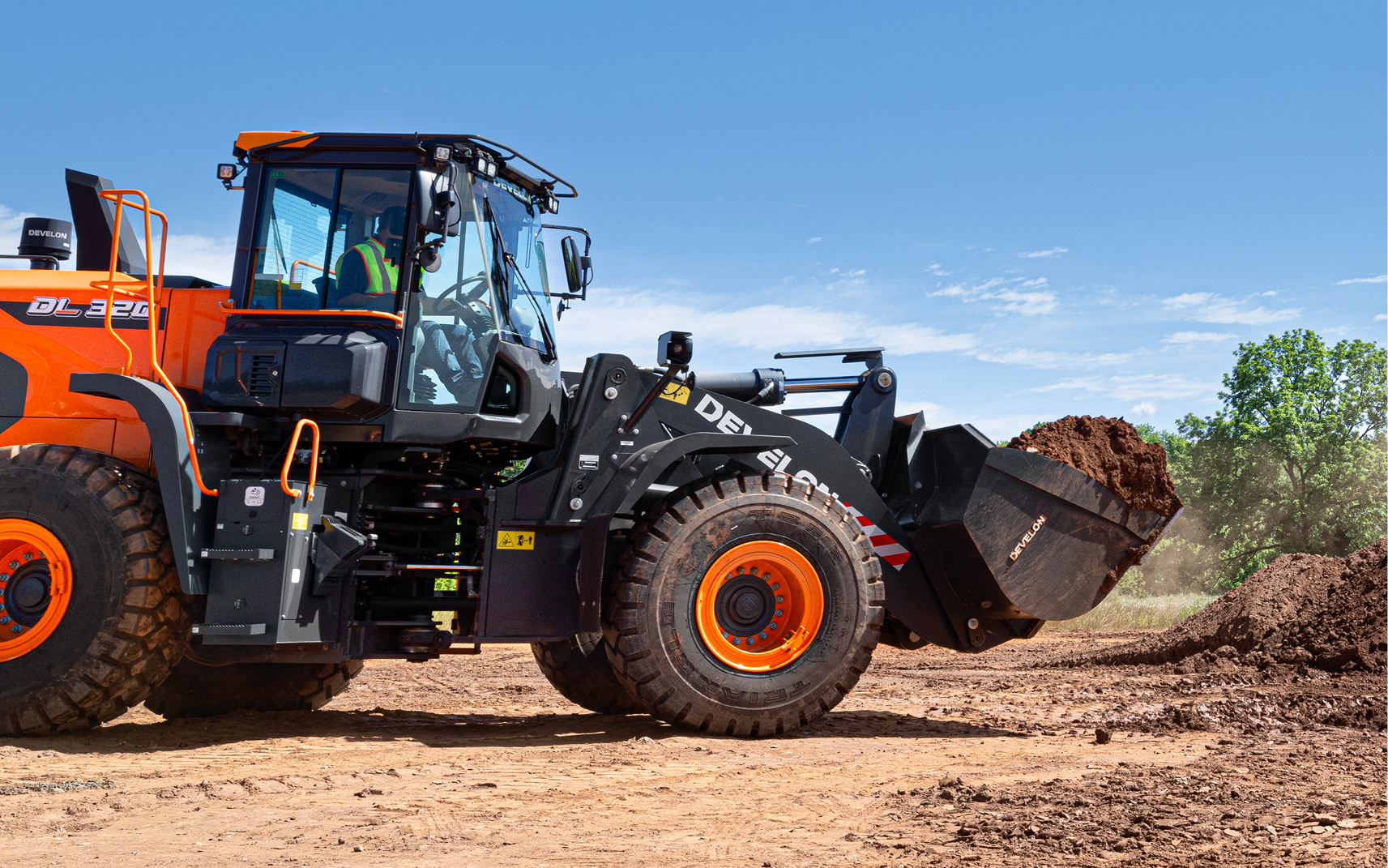 A wheel loader transports a bucket of dirt, benefiting from load isolation and ride control.
