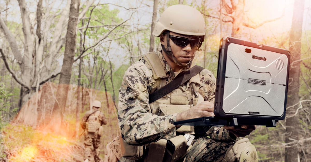 A soldier with sunglasses uses military technology in the field.
