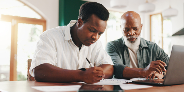 Father, son and laptop in home for finance paperwork, writing or mortgage application with senior. Budget document, men and help with loan contract or teaching investment planning with African family