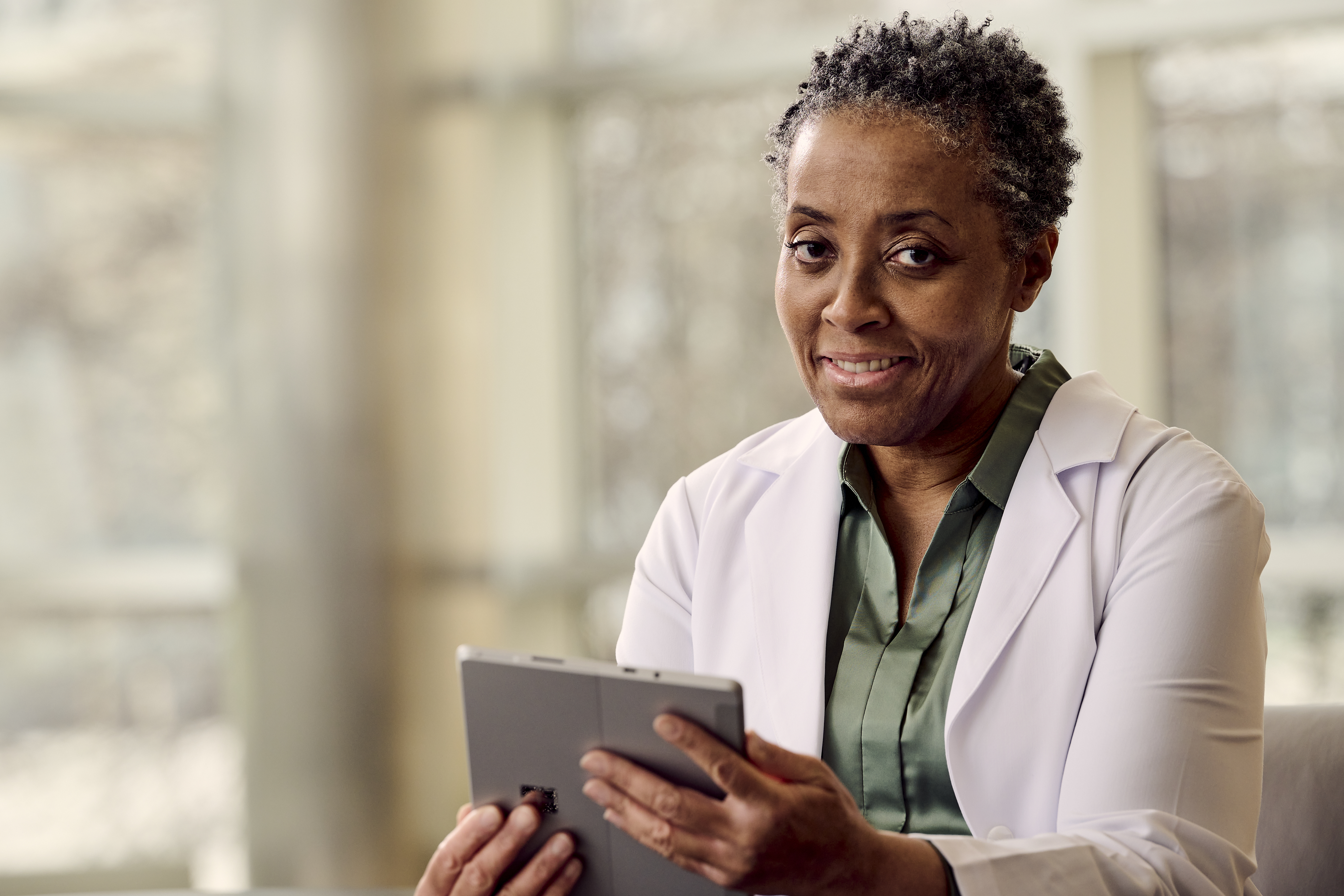 A clinician smiles while holding a tablet utilizing Verisound Digital and AI solutions