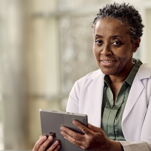 A clinician smiles while holding a tablet utilizing Verisound Digital and AI solutions