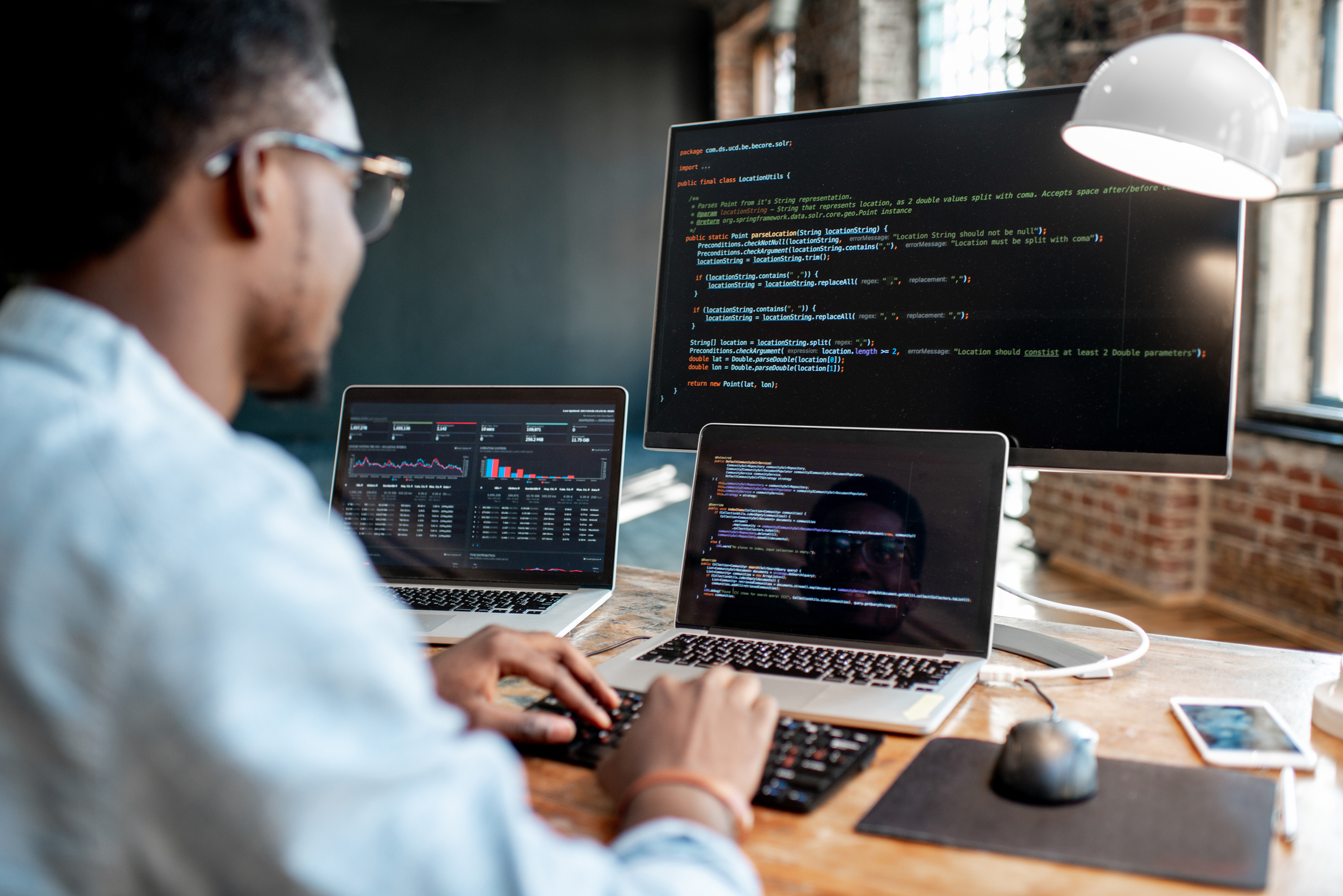 Man coding on multiple laptops and external monitor