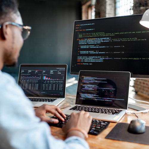 Man coding on multiple laptops and external monitor