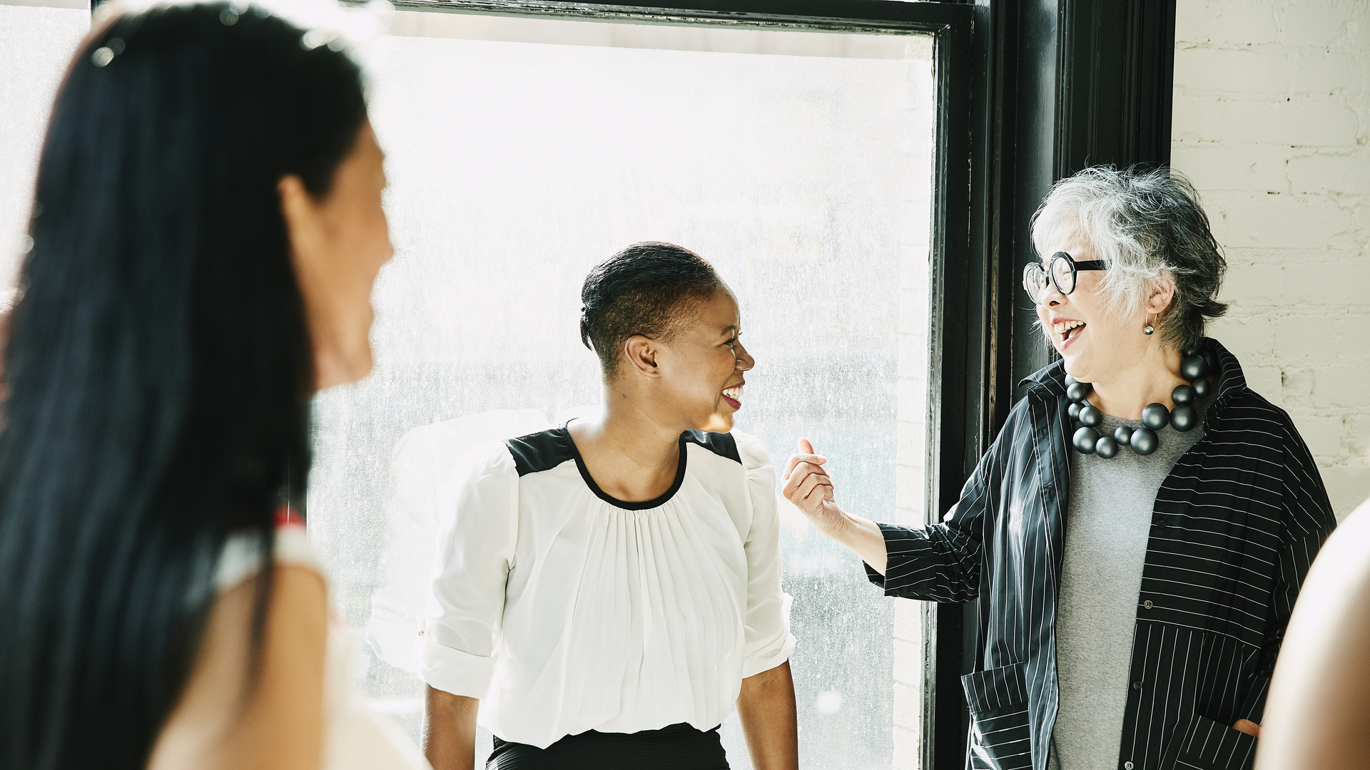 Senior businesswoman laughing with colleague during meeting in creative office