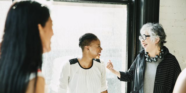 Senior businesswoman laughing with colleague during meeting in creative office