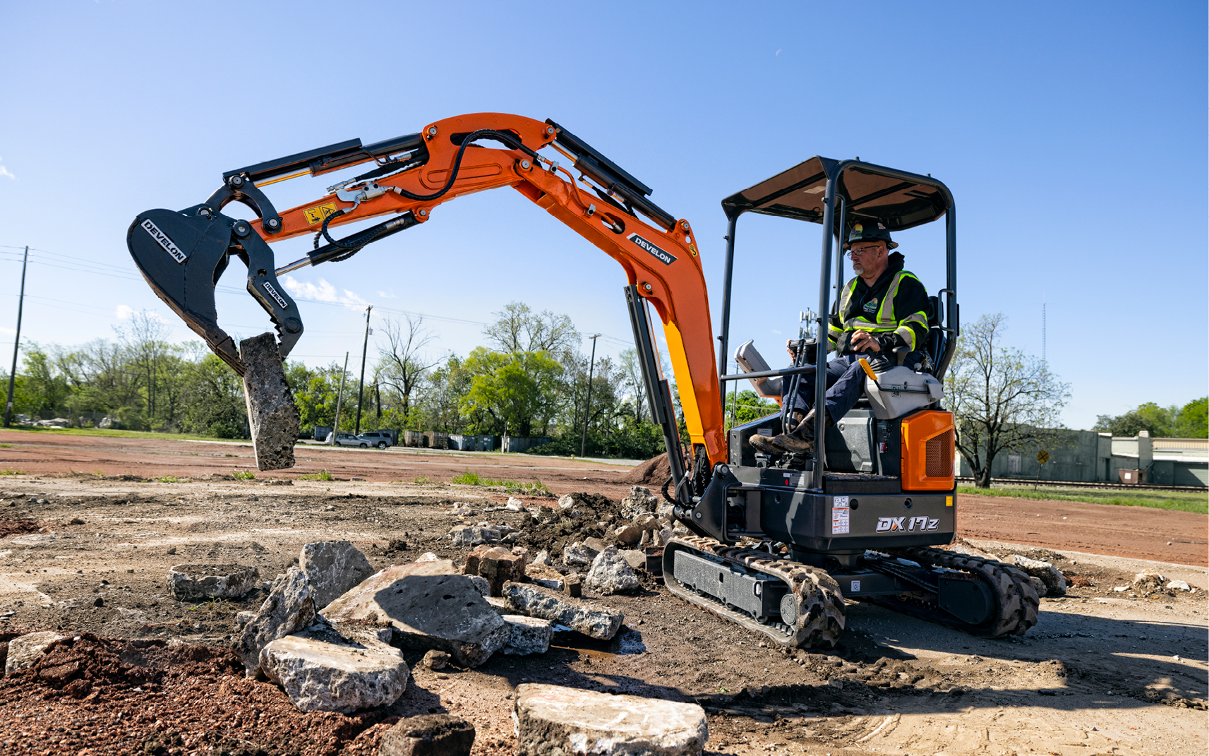 Operator picking up concrete with a DEVELON DX17Z-7 mini excavator.