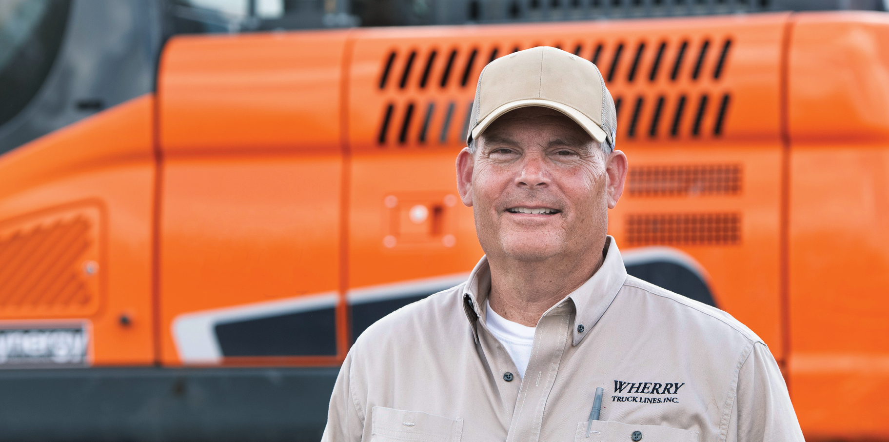 Kendell Wherry of Wherry Truck Lines standing in front of a DEVELON machine.