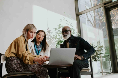Image of three services operations professionals looking at a laptop and discussing what's on screen