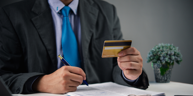 Businessman holding credit card and writing financial report. Online banking, payment management, and budget planning for personal finance analysis, transaction and business use.