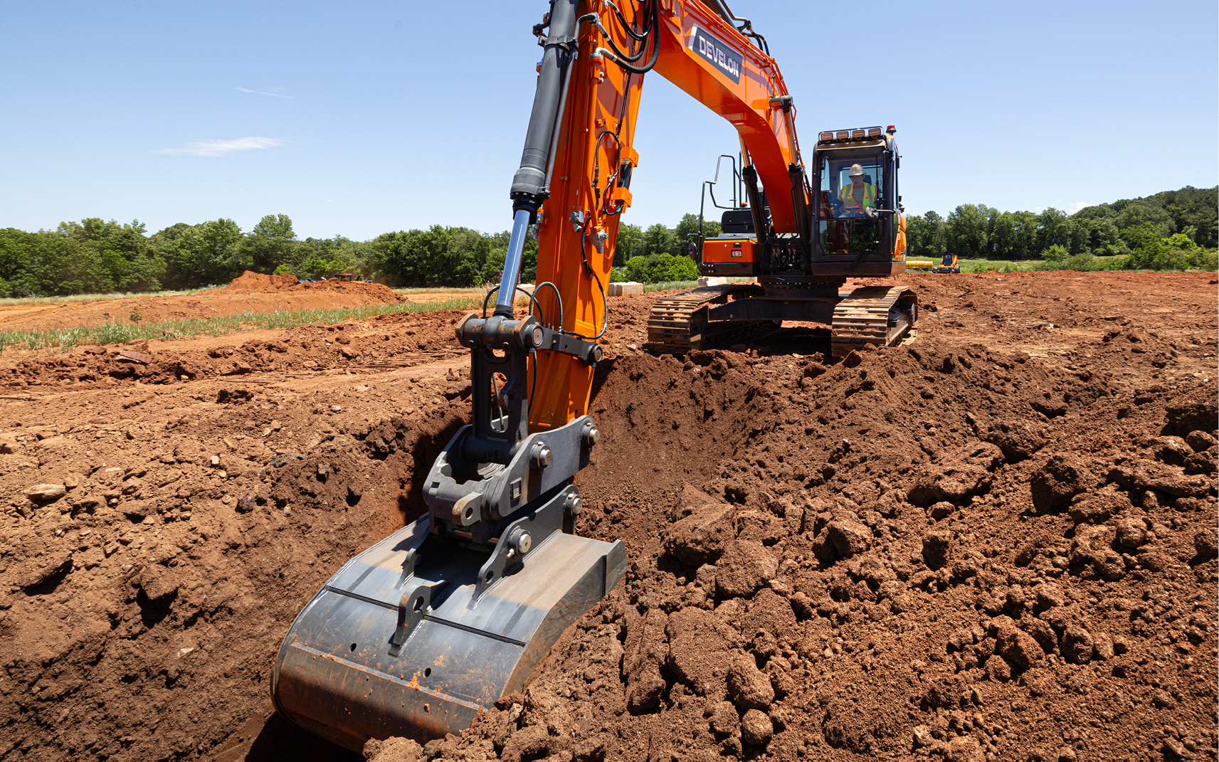 An operator uses the 2D grade control system for the DEVELON DX225LC-7X excavator.