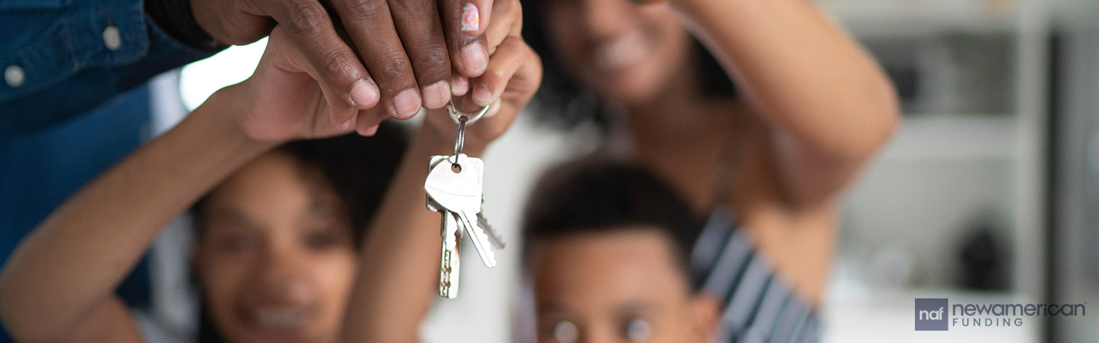 A Black family smiling and holding house keys