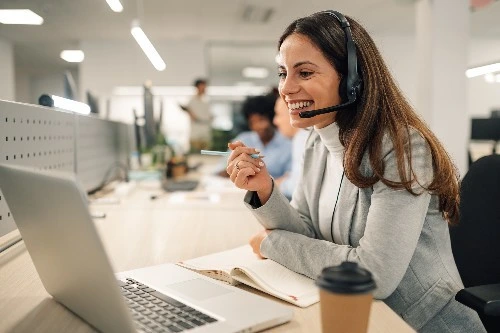 Customer success manager wearing a headset and looking at her laptop, talking to someone online