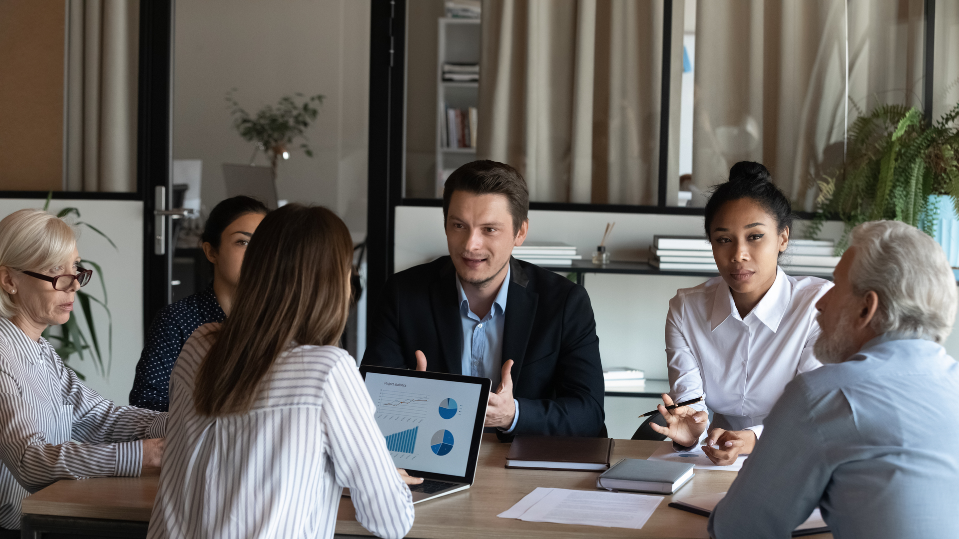 Diverse employees listening to confident businessman coworker at briefing