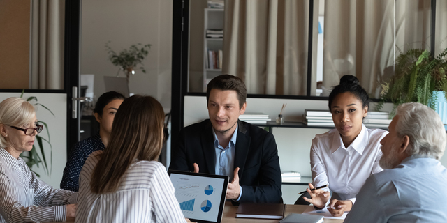 Diverse employees listening to confident businessman coworker at briefing