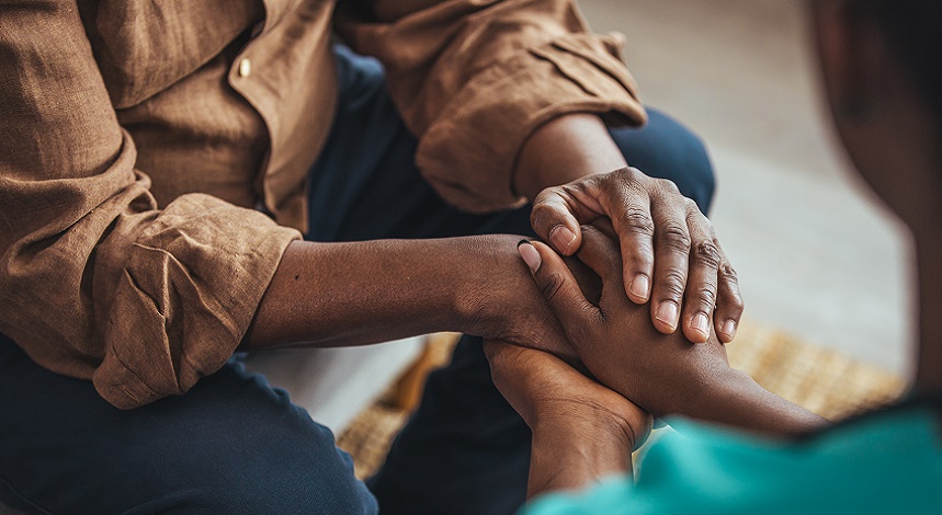 Closeup shot of a young woman holding a senior man's hands in comfort