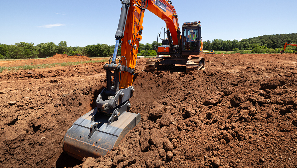 A DEVELON excavator digs a trench on a job site.
