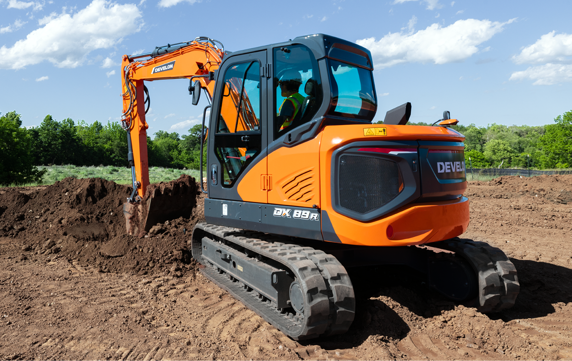 A DEVELON DX89R-7 mini excavator digs dirt on a jobsite.