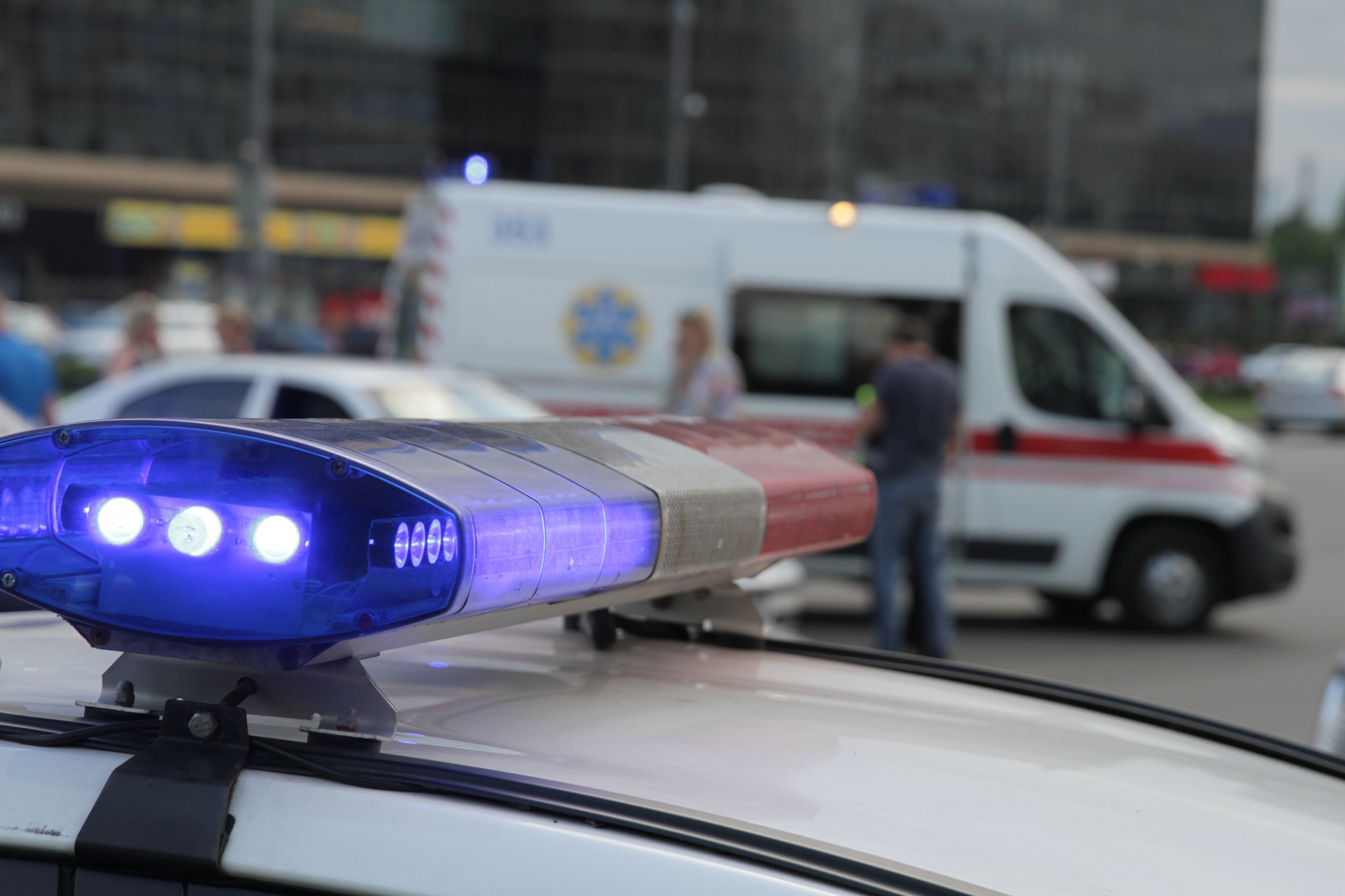A first responder uses a rugged laptop in the field with a police vehicle in the foreground.