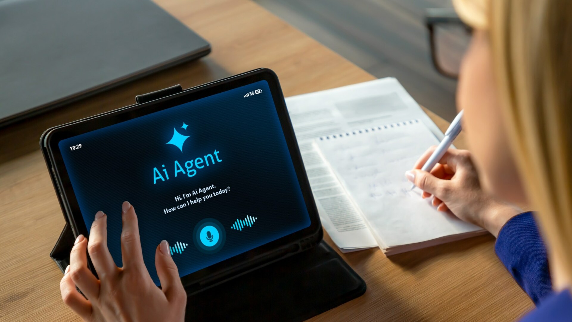 Professional businesswoman working at a desk while interacting with an AI assistant on a tablet screen. The scene shows a modern office environment with notebook, laptop, and digital tools, representing productivity, smart technology, and digital transformation in business. Ideal for concepts related to artificial intelligence, remote work, automation, business innovation, and modern office lifestyle.