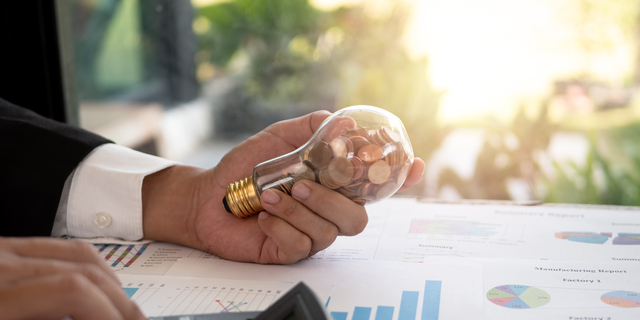 Hand of businessman hold light bulb with coin. Concept of Cost reduction and Reduce energy