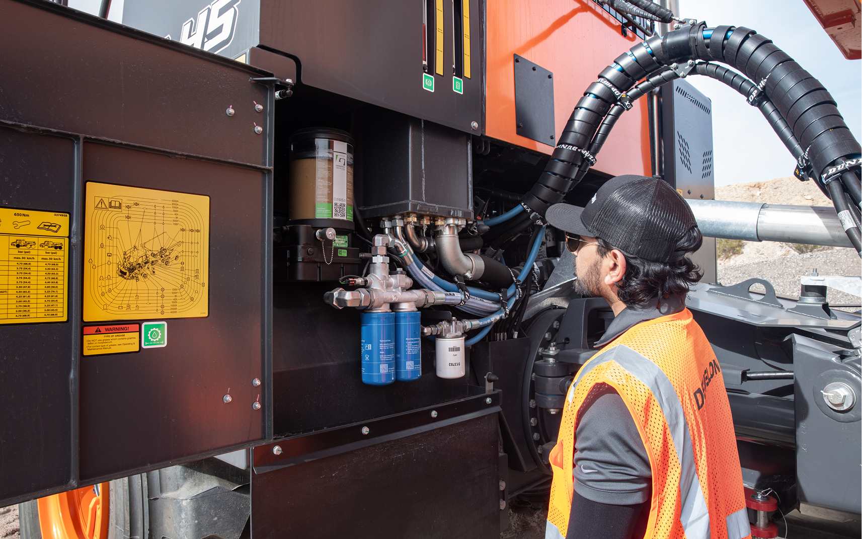 An operator looks at the ground-level service compartment on an articulated dump truck.