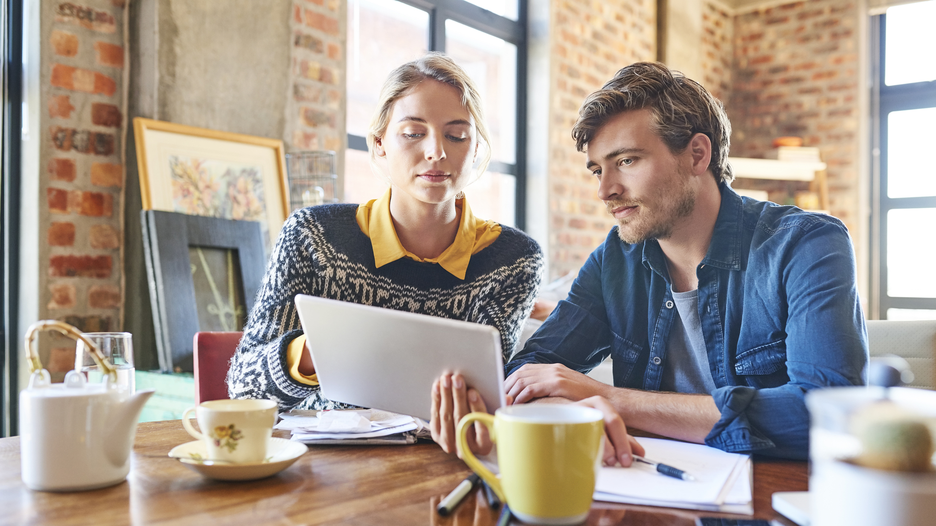 Young man and woman using digital tablet at table