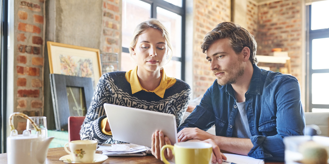 Young man and woman using digital tablet at table
