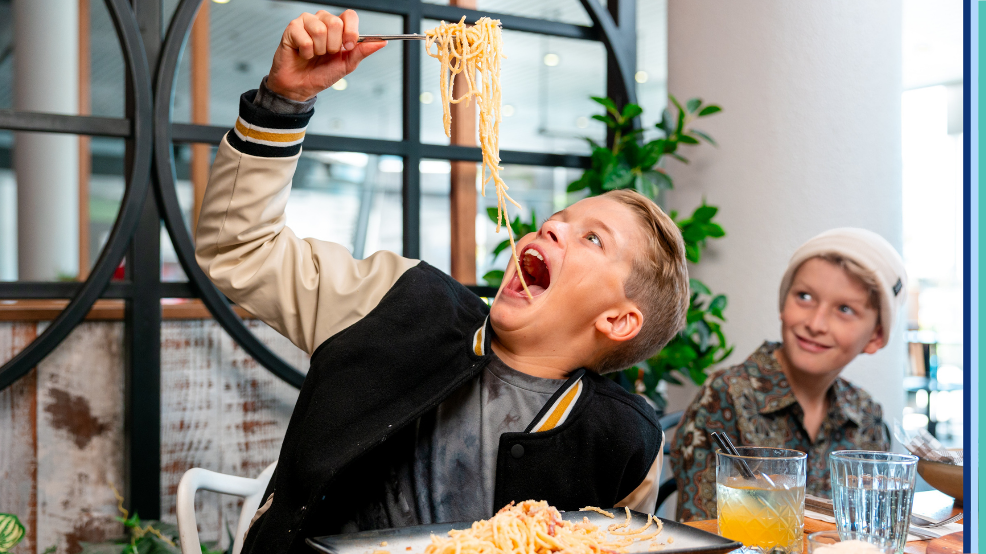 Two children enjoying pasta at Motto Motto