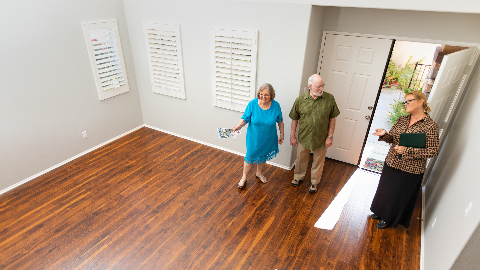 Female Real Estate Agent Showing Senior Adult Couple A New Home