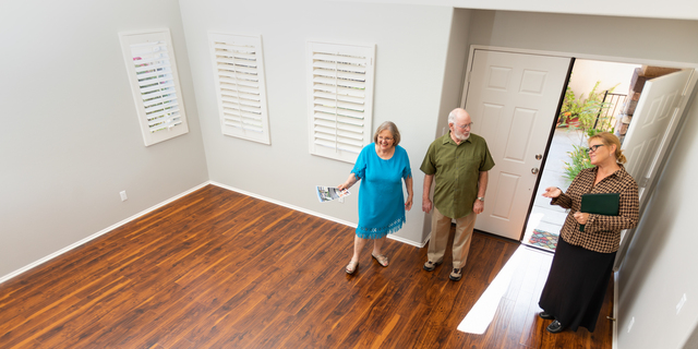 Female Real Estate Agent Showing Senior Adult Couple A New Home