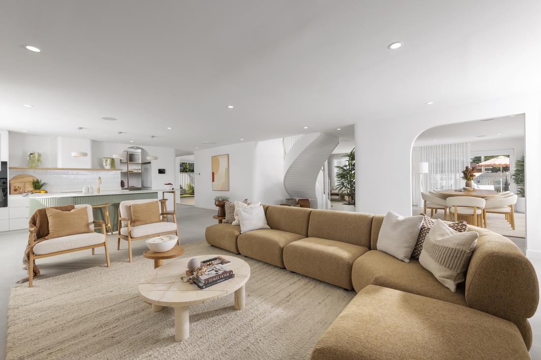 A living room with a tan couch with cushions and a round wooden coffee table.