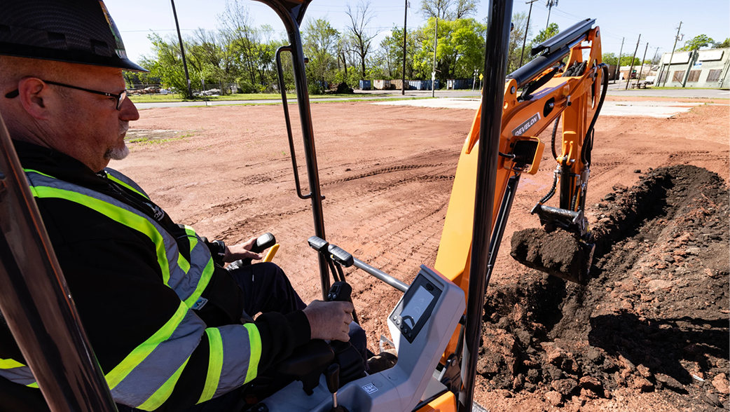 An operator trenching with a DEVELON mini excavator.